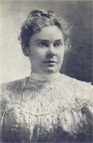 A woman in white dress and hair up.